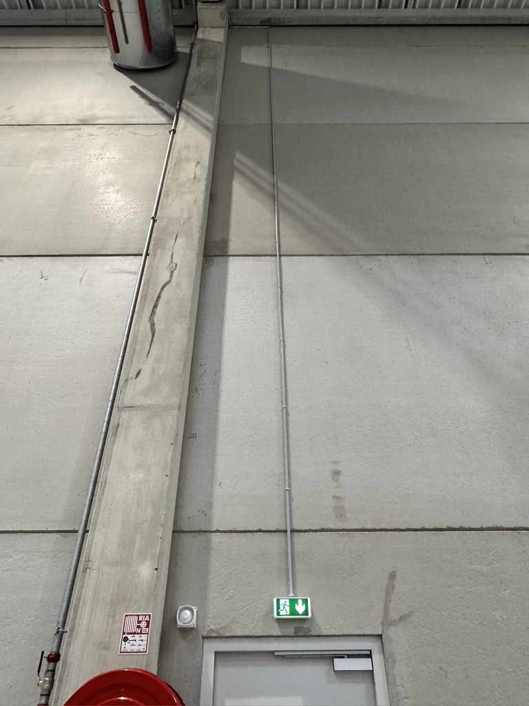Plafond industriel — chemins de câbles, bloc de secours et signalétique